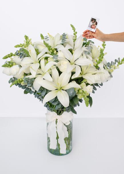 Rosas blancas y lilys blancas en jarrón cilindro con mini foto